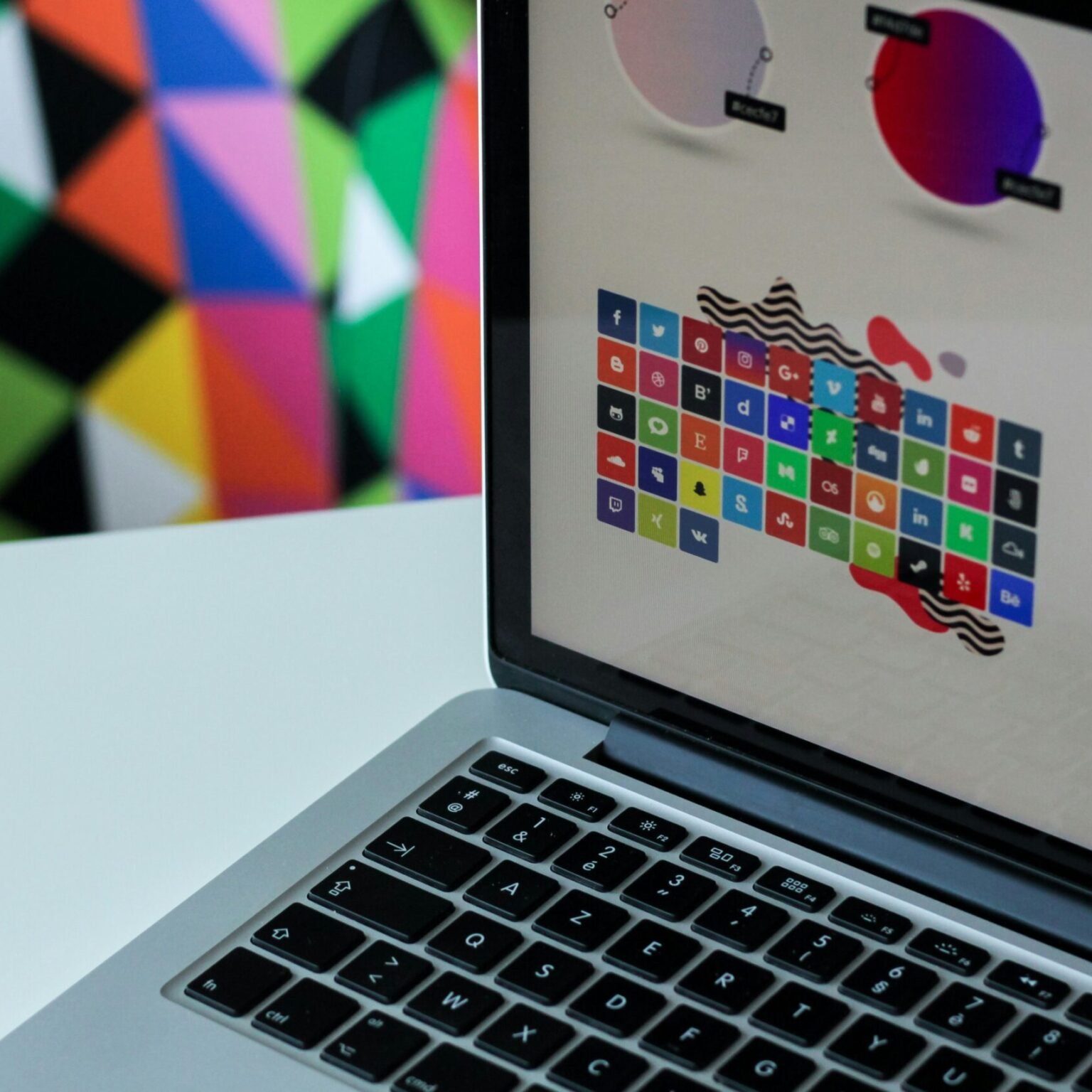 Modern UI design on a laptop screen showing colorful app icons and user interface mockups for RevampX web design services.